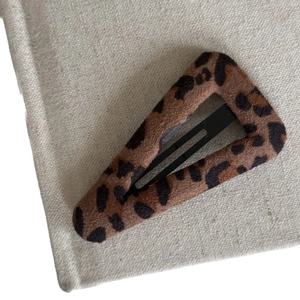 Triangle leopard print fabric hair clip with soft texture on a natural beige background