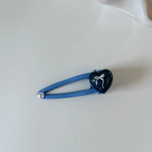 Dettaglio del fermaglio per capelli blu a cuore con motivo a fiocco e piccola perla