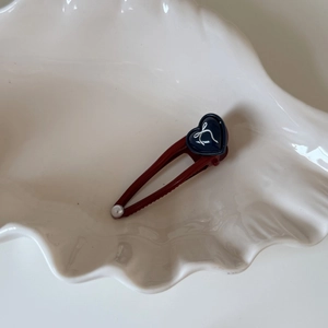 Dettaglio di un fermaglio per capelli a fiocco rosso scuro con cuore e perla piccola