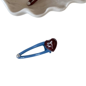Fermaglio per capelli cuore azzurro con motivo a fiocco bianco su un piatto di ceramica