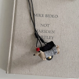 Détail du pendentif teckel en tissu marron avec des vêtements à carreaux noirs et blancs
