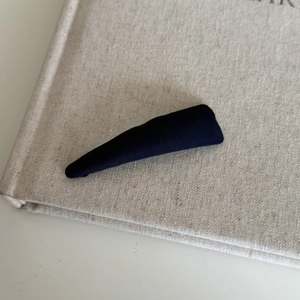 Close-up of navy blue striped fabric hair clip on a minimalist textile background