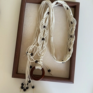 Bohemian macramé waist chain with butterfly beads and wooden ring on a beige velvet tray
