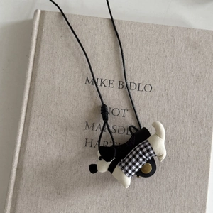 Détail d'un pendentif teckel blanc avec vêtements à carreaux et cordon noir