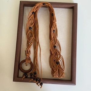 Detail of bohemian braided rope belt with dark wooden ring buckle and embedded beads