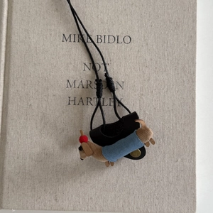 Détail du pendentif teckel en peluche marron avec gilet en denim bleu et cordon tressé