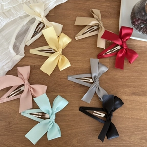 Set of 8 colorful satin bow hair clips in various pastel colors on a wooden background