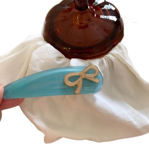 Sky blue acetate drop hair clip with brown bow and Creation France text on white base