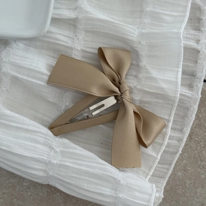 Detailed view of a sweet champagne satin ribbon bow hair clip with a metal BB fastener