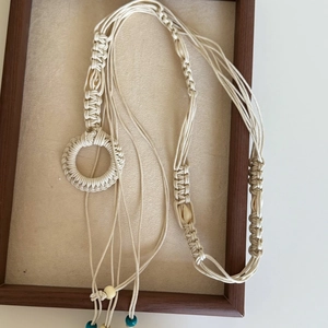 Detail of bohemian handmade woven waist chain with shells and beads on wooden tray