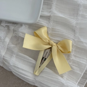 Sweet light yellow satin bow hair clip with metal BB grip on a minimalist background