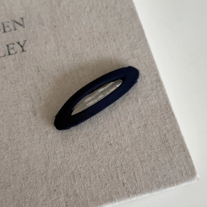 Macro shot of navy blue fabric-covered oval BB clip with fine twill texture details