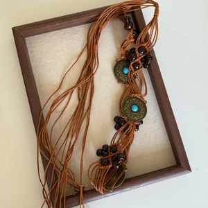 Detail of bohemian braided waist chain with turquoise-style stones and wood beads