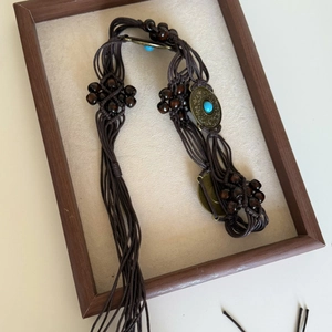 Detail of bohemian woven waist chain featuring turquoise stones and ethnic wood beads