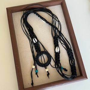Detail of bohemian hand-woven waist chain with natural shells and blue beaded accents