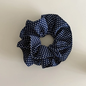 Chouchou bleu marine à pois blancs avec nœud papillon sur fond plat neutre
