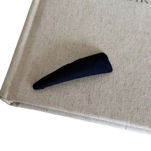 Minimalist black fabric wrapped hair clip in water drop shape on rustic background
