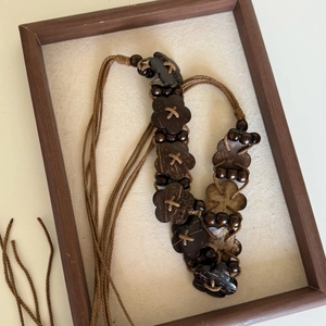 Detail of bohemian waist chain featuring wooden flower charms and brown braided cords