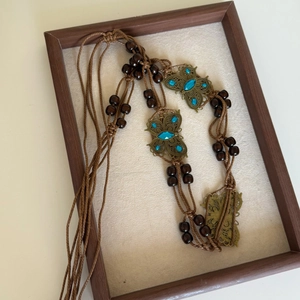 Detail of bohemian braided waist chain featuring wooden beads and blue stone butterflies