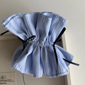 Detail of light blue striped fabric pouch with elegant black silk ribbon drawstring tie