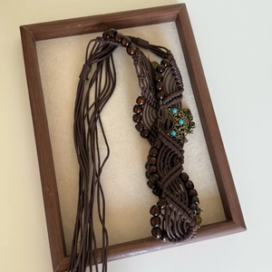 Close-up of bohemian hand-woven waist chain with dark wood beads and turquoise buckle