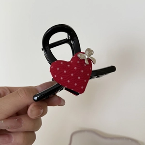 Close-up of a red polka dot heart fabric and silver metal bow on a black hair claw clip