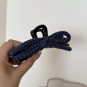 Detail of navy blue polka dot bow hair claw clip made of durable polished plastic