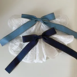 Détail de pinces à cheveux avec nœuds en denim, bordure dentelle et coutures jaunes