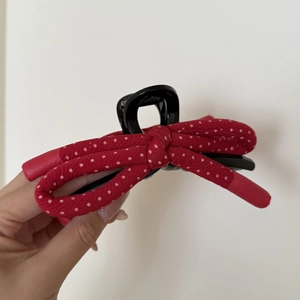 Detail of red polka dot bow hair claw clip with black polished finish and inner teeth