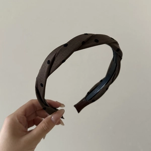 Detail of twisted dark coffee fabric headband with black polka dots and non-slip teeth