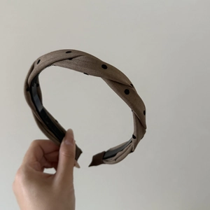 Detail of a brown polka dot twisted headband with non-slip teeth for hair styling