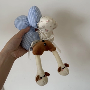 Close-up of a handmade plush doll keychain featuring blue plaid and floral fabric patterns