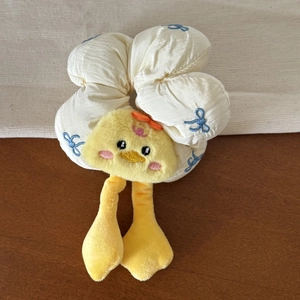 Detailed view of plush yellow duck hair scrunchie with blue bow embroidery patterns