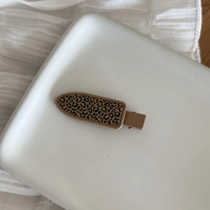 Vintage leopard print hair clip with brown cheetah pattern on a minimalist white tray