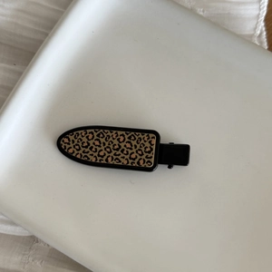 Vintage leopard print hair clip with black metal base on a white ceramic tray