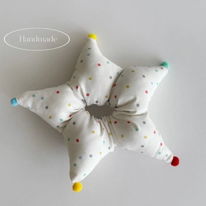 Handmade plush star scrunchie with colorful polka dots and pom-poms on grey background