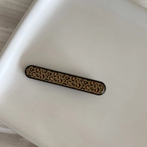Macro shot of rectangular leopard print hair clip on a minimalist white tray