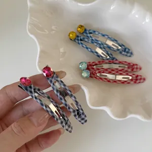 Plaid fabric hair clips with colorful rhinestones set on a ceramic shell tray