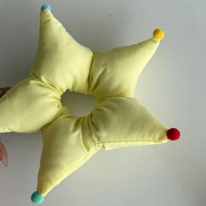 Star-shaped light yellow hair scrunchie with colorful mini pompoms on each point