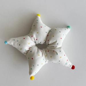 Detail of star-shaped hair scrunchie with colorful polka dots and pompom accents