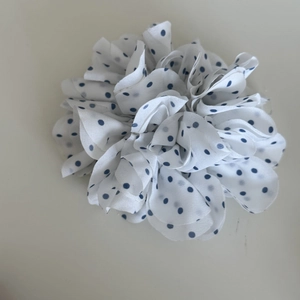 Close-up of white chiffon scrunchie with blue polka dots and layered floral pleats
