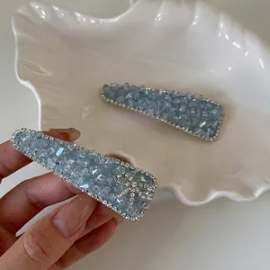 Sparkling light blue crystal hair clips with rhinestone bow on an elegant shell tray