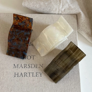 Close-up of vintage acetate hair clips in tortoiseshell and cream on linen books