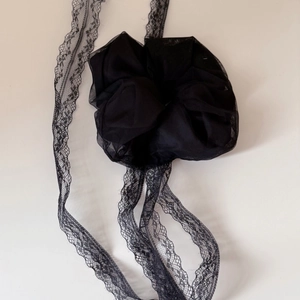 Close-up of black lace scrunchie with long mesh ribbons and intricate floral detailing