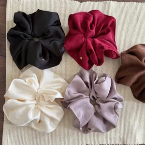 Detail of premium satin scrunchies in five colors with refined gold metal labels