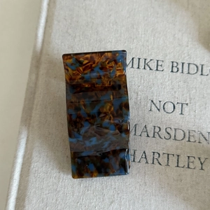 Close-up of vintage tortoiseshell acetate hair claw clip on minimalist beige fabric background
