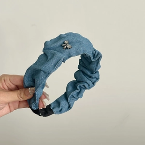Dettaglio del cerchietto in denim plissettato con fiocco di strass e base antiscivolo