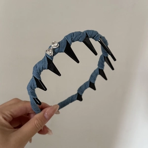 Detail of blue denim headband featuring black inner plastic teeth and silver metal bow