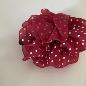 Detail view of the red chiffon floral hair clip with white polka dots pattern