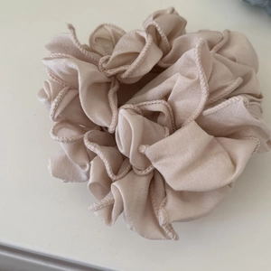 Dettaglio di uno scrunchie plissettato champagne con trama delicata del tessuto
